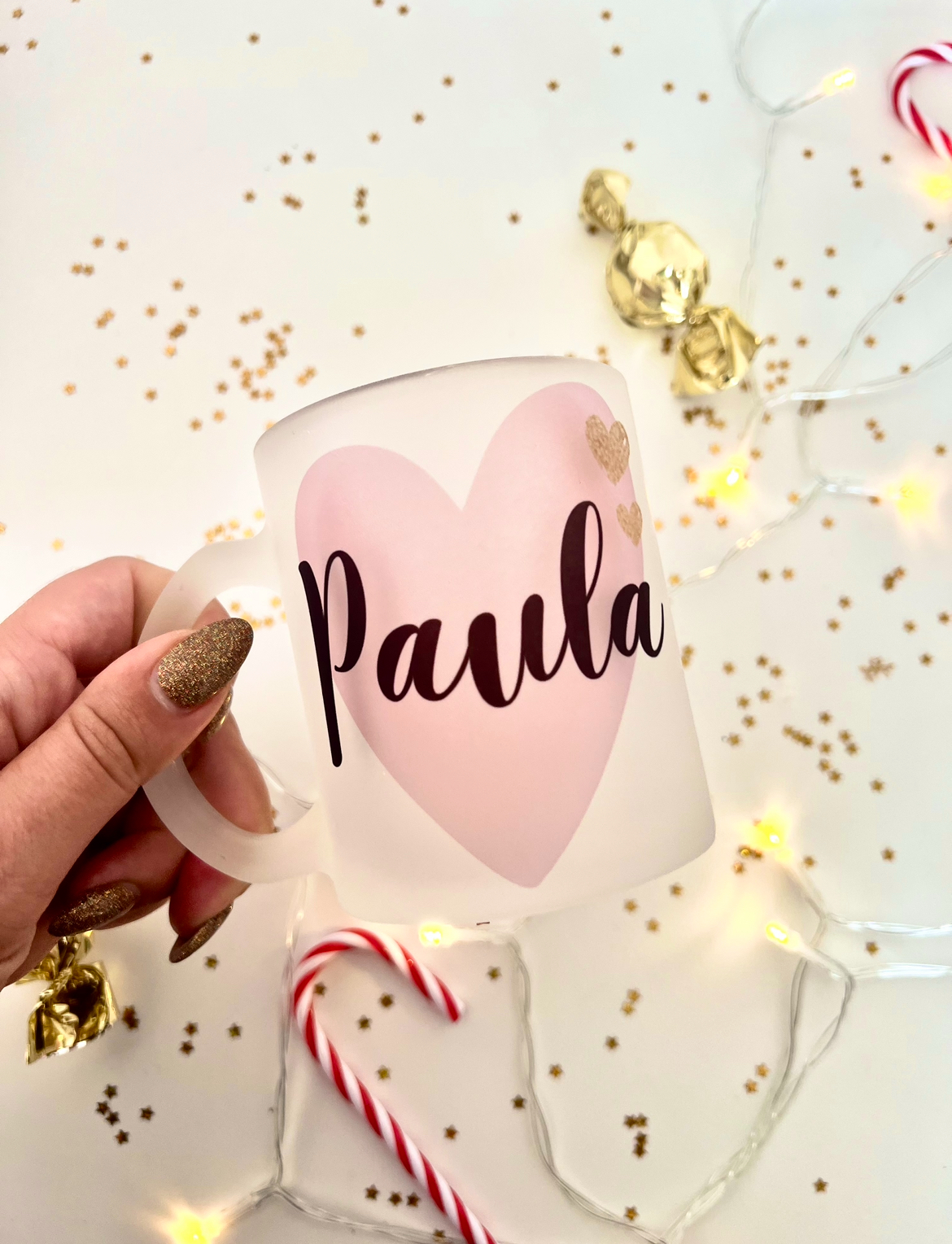 Box Caneca Coração Caneca de vidro fosco com coração rosa e nome Paula, mão segurando, fundo com confetes dourados e doces