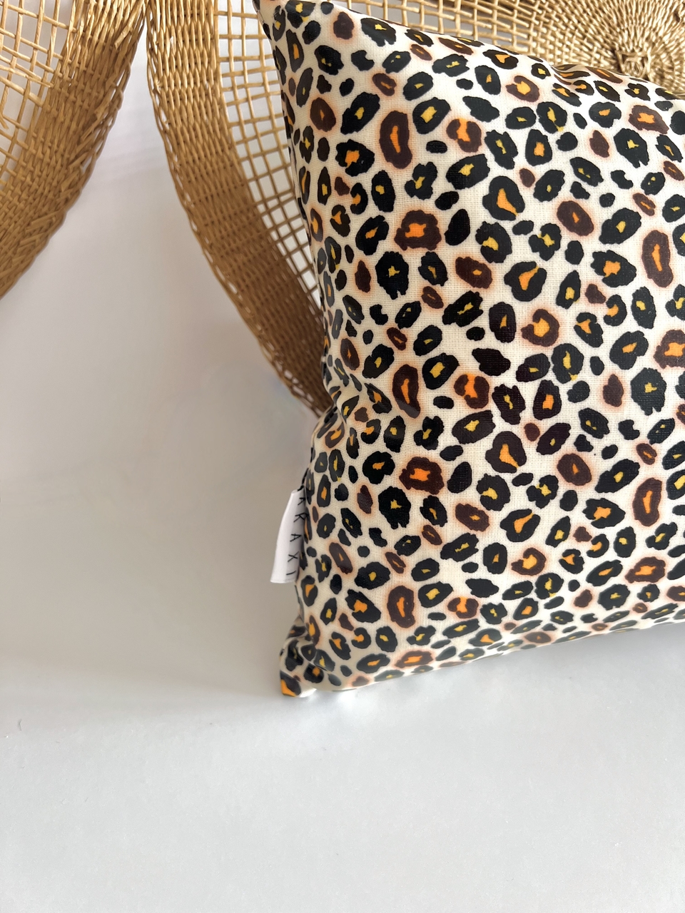 Almofada Leopardo Almofada com estampa animal print sobre superfície branca e decoração em fibra natural