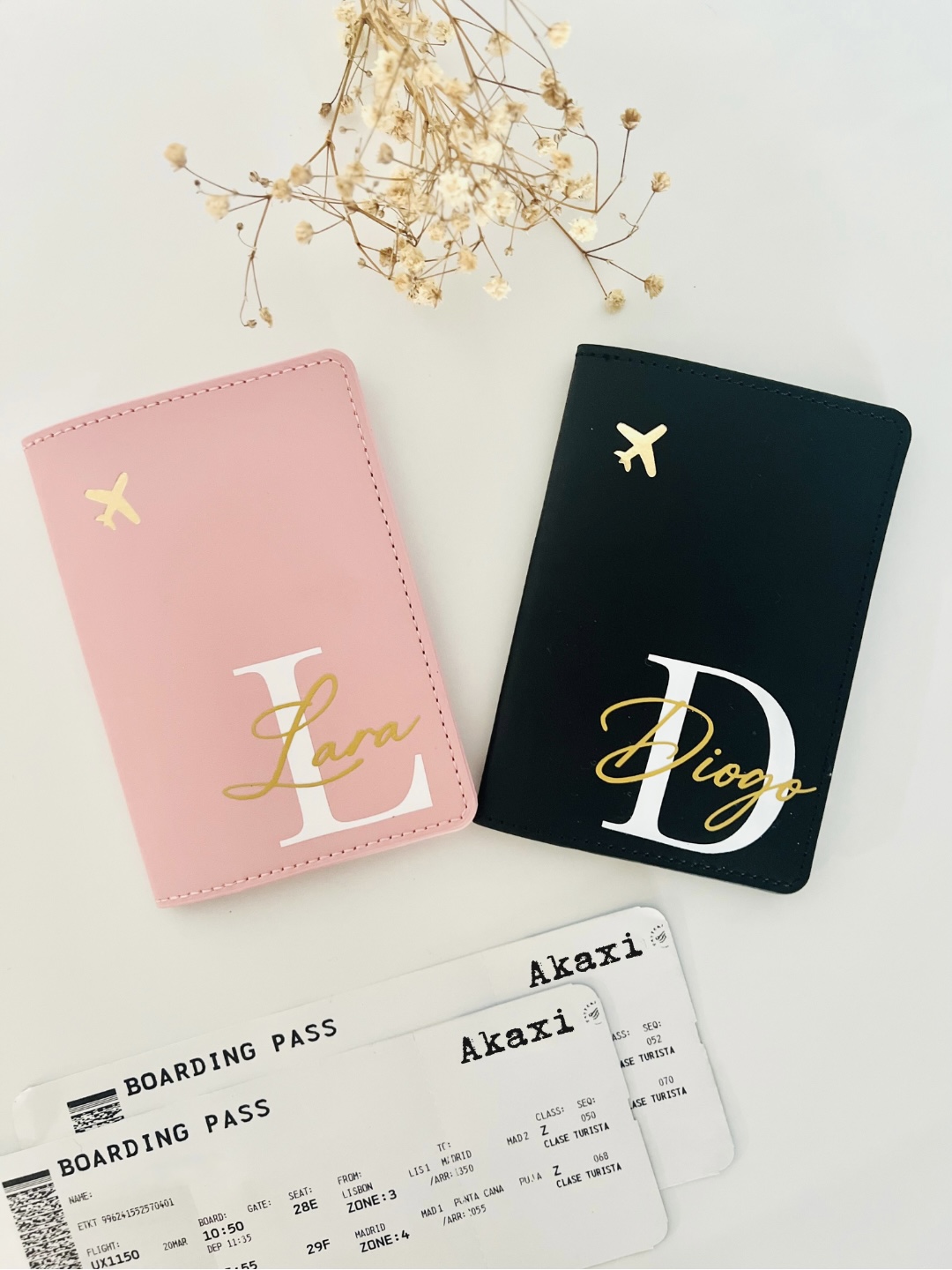 Capa de Passaporte Dois porta-passaportes em rosa e preto com nomes personalizados, duas cartas de embarque e flores secas