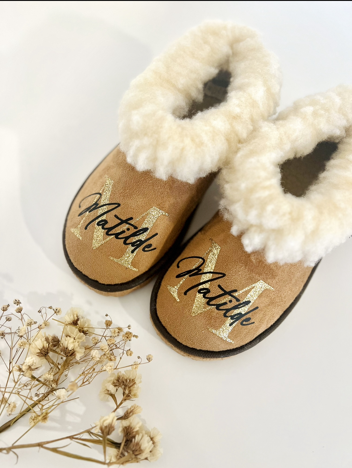 Pantufas com pelo - Inicial + Nome Pantufas castanhas com pelo branco e texto 'Matilde', flores secas ao lado