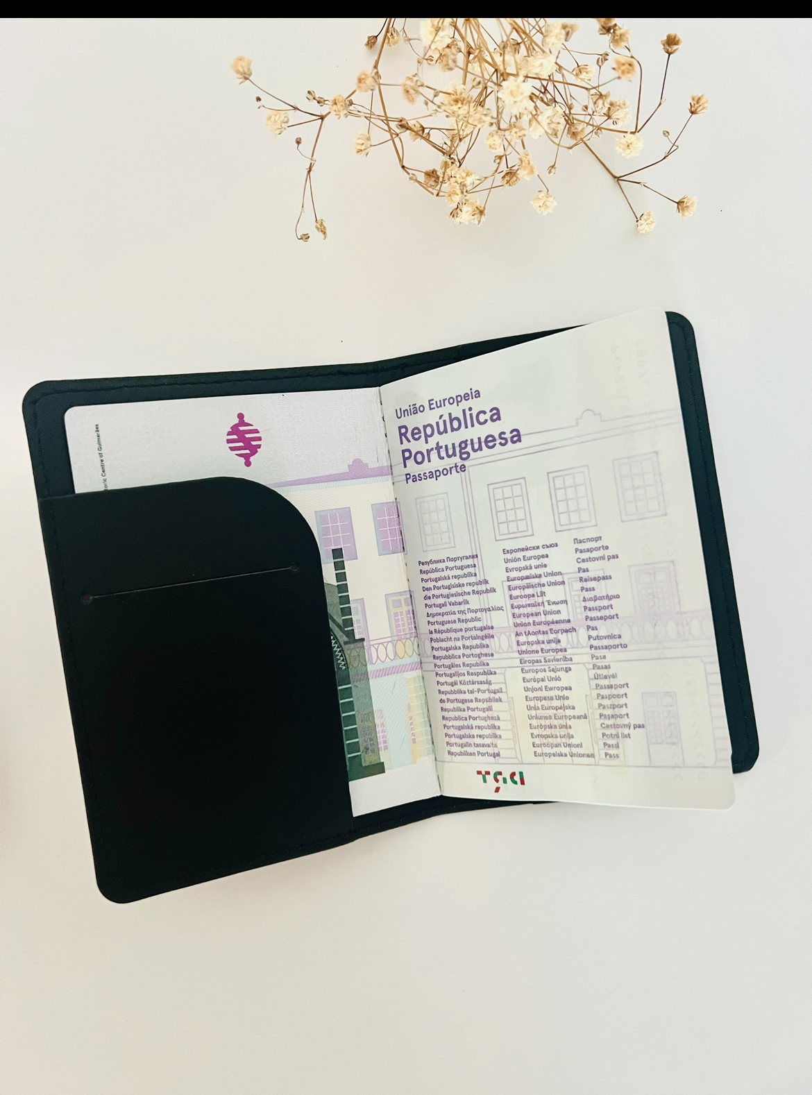 Capa de Passaporte Capa preta de couro com passaporte português aberto e flores secas ao fundo