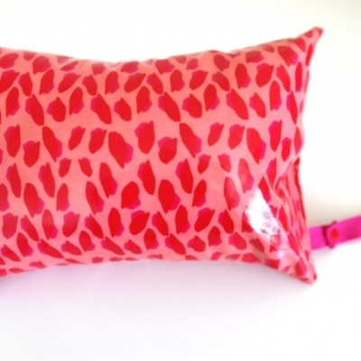 Almofada retangular rosa com padrão em tons de rosa e laço lateral