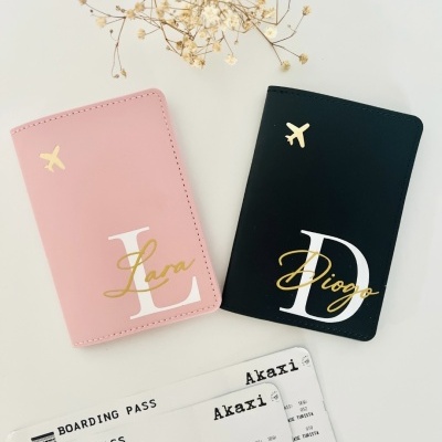 Dois porta-passaportes em rosa e preto com nomes personalizados, duas cartas de embarque e flores secas