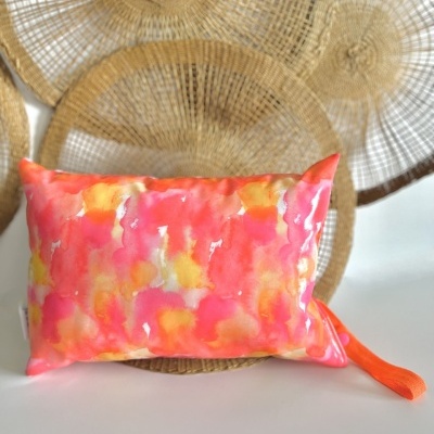 Almofada colorida com padrão rosa, laranja e amarelo com fundo de decorações circulares de fibras trançadas