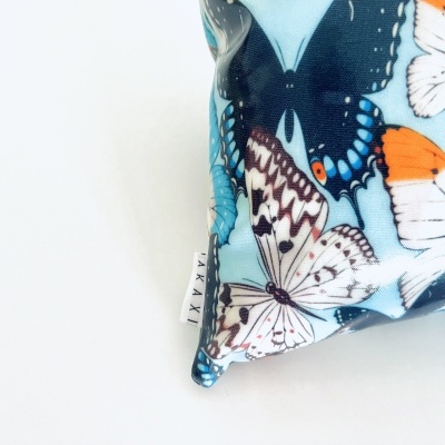 Almofada azul com estampado de borboletas e etiqueta lateral MAXAI