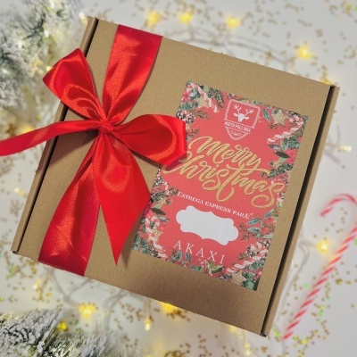 Caixa de presente castanha com laço vermelho e rótulo decorativo vermelho e verde com texto natalício