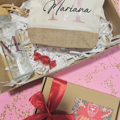 Conjunto de presente com saco de tecido e garrafa personalizadas com o nome Mariana, um cartão de Natal e embalagem com fita vermelha.