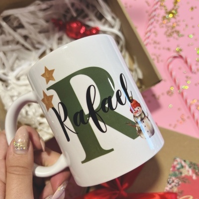 Caneca branca personalizada com nome Rafael, com decoração de Natal, segurada à mão