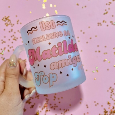 Caneca de vidro fosco com texto colorido sobre fundo rosa com confetes dourados