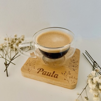 chávena de vidro com café espresso sobre base de madeira gravada com o nome Paula