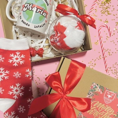 Presente de Natal com caneca personalizada, bola decorativa, meias vermelhas com flocos de neve e caixa de presente com laço vermelho