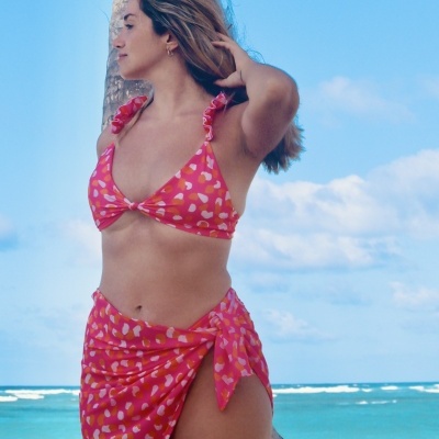 Roupa de banho feminina vermelha com padrão de corações e palmeira ao fundo