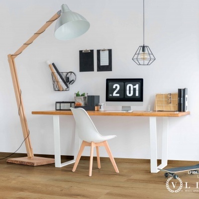 Espaço de escritório com mesa de madeira clara, cadeira branca, candeeiro de pé de madeira e computador