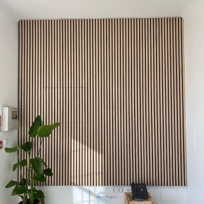 Painel de madeira com faixas verticais, planta em vaso de vime e caixa de vime com telefone