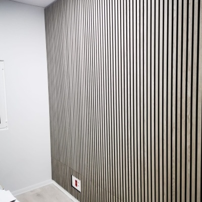 Parede com painéis de madeira clara e faixas pretas em ambiente interior