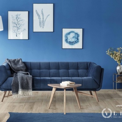 Sala de estar com sofá azul, mesa de centro e quadros botânicos