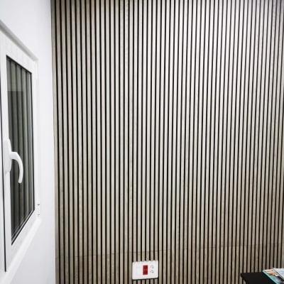 Parede de madeira com riscas verticais e janela branca numa sala interior