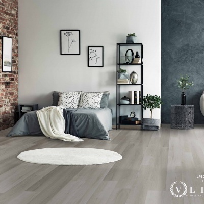 Quarto moderno com cama cinza, prateleira preta com decoração, plantas e chão em madeira cinza claro