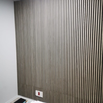 Parede com painéis verticais de madeira clara com linhas pretas entre os painéis
