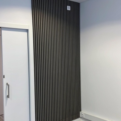 Parede com painel de madeira preta e porta deslizante branca num ambiente interior