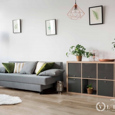 Sala moderna com sofá cinza, almofadas, candeeiro, aparador e plantas