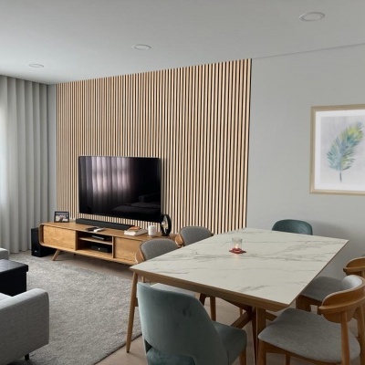 Sala de estar e de jantar com mesa de mármore, cadeiras coloridas, móvel de madeira e TV