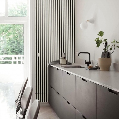 Cozinha moderna com armários cinza, bancada branca e cadeira preta junto a janela