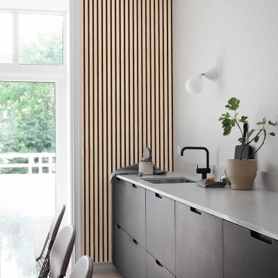 Cozinha moderna com armários cinza escuro, tampo branco e painel de madeira com ripas verticais.