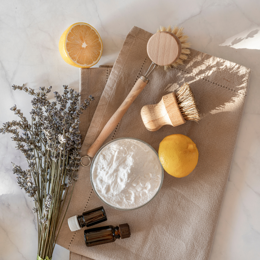 Produtos naturais para limpeza com escovas de madeira, vidro com pó branco, lavanda, limão e toalha bege