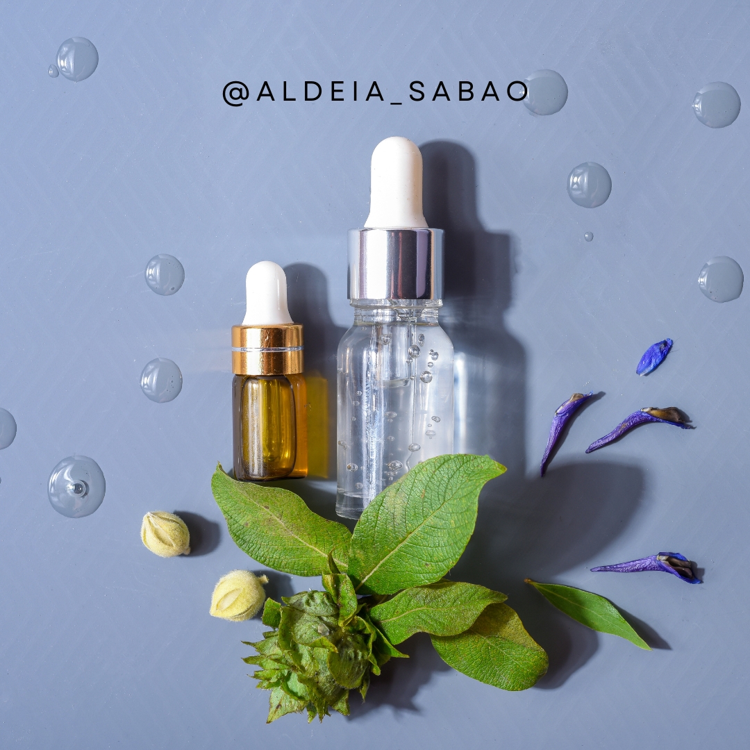 Frascos conta-gotas em vidro com folhas e gotas ao redor sobre fundo cinza azulado