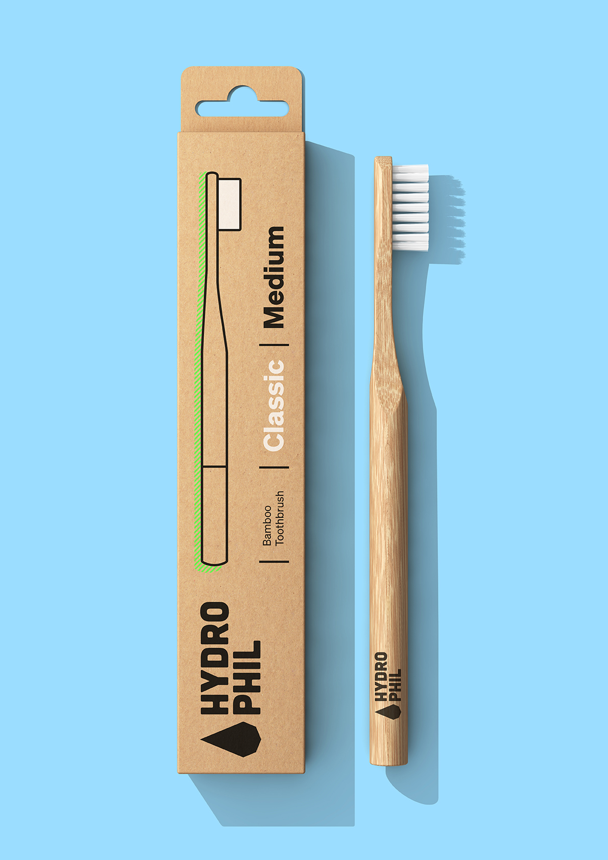 Escova de Dentes de Bambu Hydrophil - Média Escova de dentes de bambu com cerdas brancas ao lado da embalagem de papel reciclado