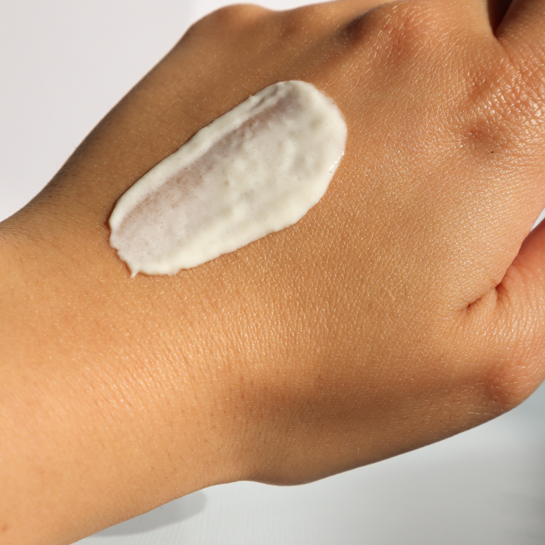 Creme branco aplicado na pele da mão em fundo branco