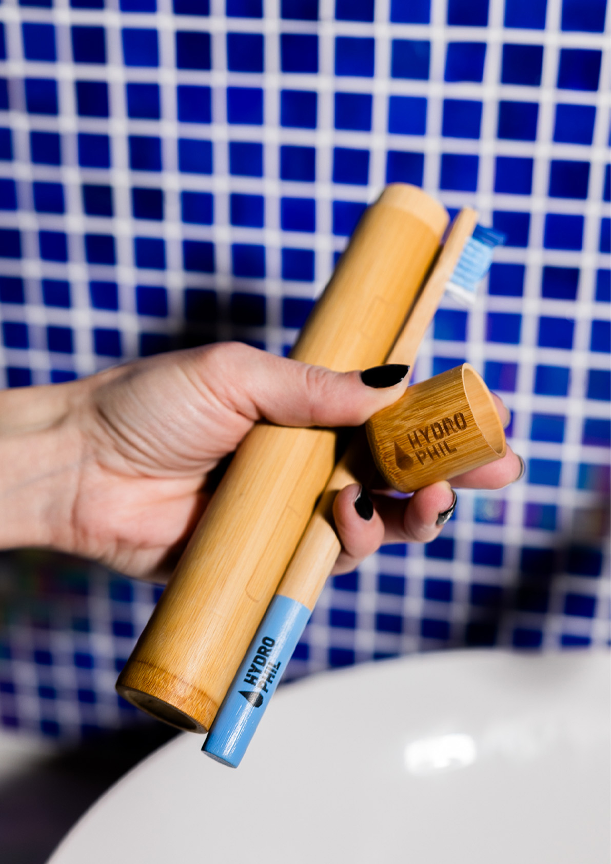 Porta Escova De Dentes de Bambu Hydrophil Mão a segurar estojo, escova de dentes de bambu e tampa com texto Hydro Phil