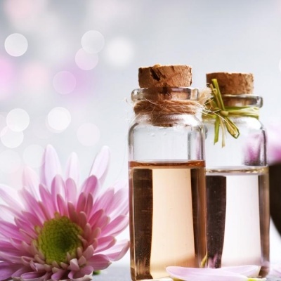 Duas garrafas de vidro com líquidos e flores cor-de-rosa