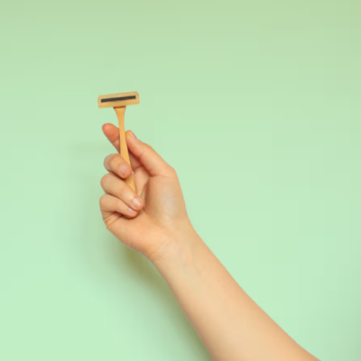 Mão a segurar uma lâmina de barbear com cabo de madeira clara