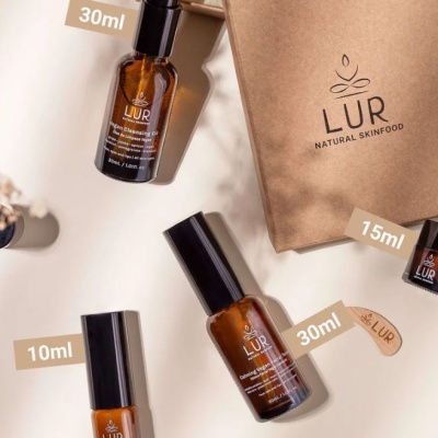 Produtos de cuidado de pele LUR em frascos castanhos com tampas pretas, embalagem de papel castanho e fundo claro