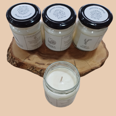 Velas artesanais em frascos de vidro com tampas pretas sobre base de madeira rústica