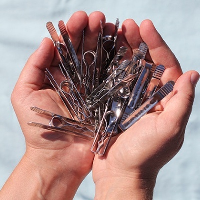 Mãos segurando molas metálicas prateadas variadas