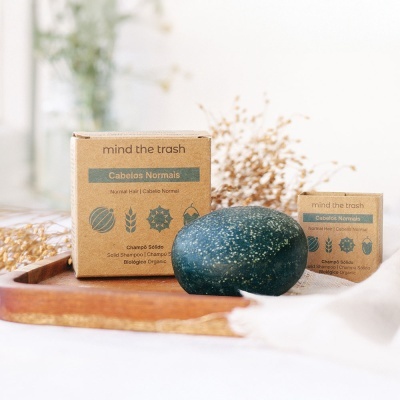 Champô sólido para cabelos normais mind the trash com embalagem de cartão e barra verde sobre bandeja de madeira