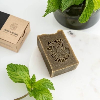 Sabonete natural com selo gravado e hortelã fresca ao redor
