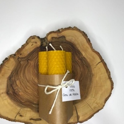 Velas de cera de abelha amarelas texturizadas embaladas em papel castanho sobre madeira