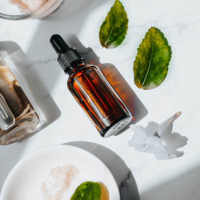 Frasco âmbar com conta-gotas e elementos naturais sobre superfície branca