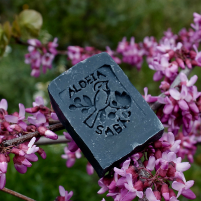 Sabonete preto com gravação em relevo sobre flores lilases