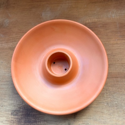 Prato de barro vermelho sobre madeira clara