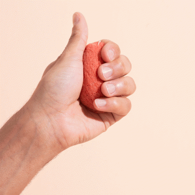 Mão a segurar uma esponja ou pedra vermelha porosa