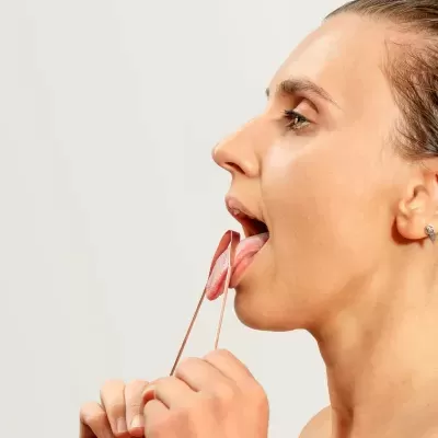 Mulher a usar ferramenta de plástico rosa para exercícios faciais.