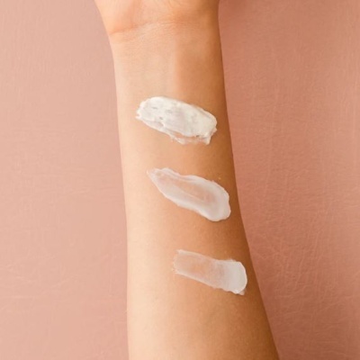 Braço com três amostras de cremes brancos em texturas diferentes