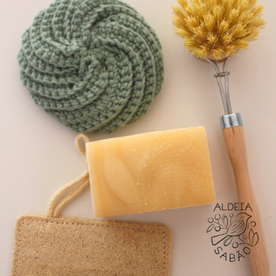 Conjunto de produtos de limpeza com esponja, sabonete, escova e disco tricotado sobre superfície clara