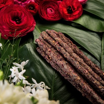 Conjunto de varas texturizadas sobre folhas verdes com flores vermelhas, rosas e brancas ao redor