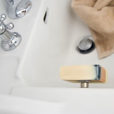 Sabonete multicolor em banheira branca com torneiras cromadas e toalha bege